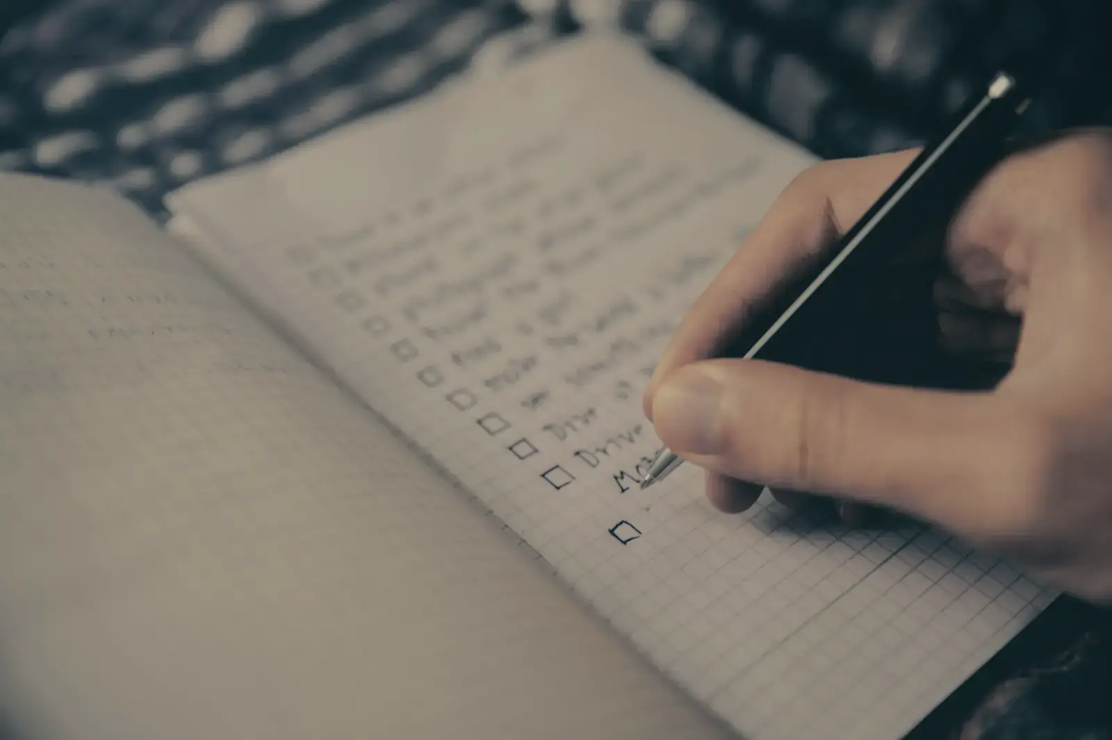Uma mão escrevendo um plano em um caderno